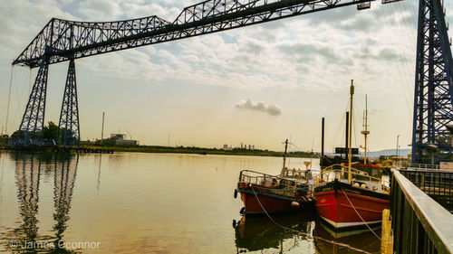 Sailboats moored in river against sky