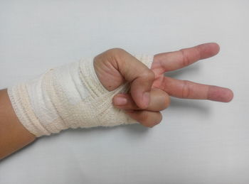 Cropped image of person hand covered with bandage showing victory sign
