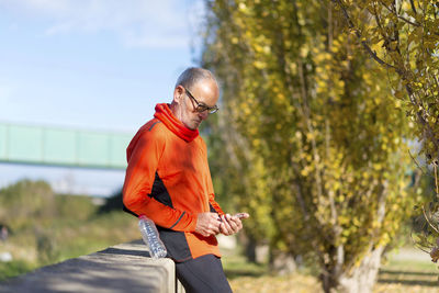 Side view of senior man using phone in park