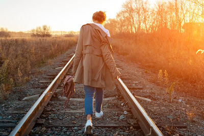 Rear view of man walking on railroad track