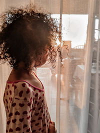 Midsection of a little girl looking through window