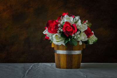 Red roses and white roses artificial on a brown background with space for text input.