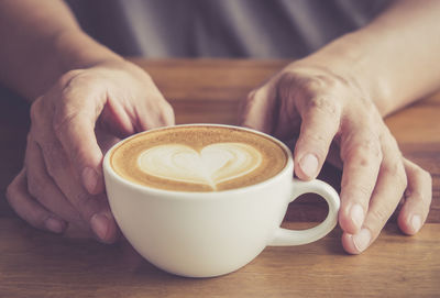 Midsection of woman with coffee cup on table