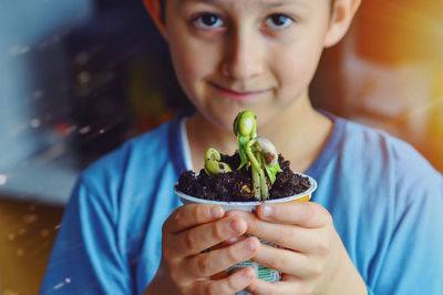 Close-up portrait of boy holding plant
