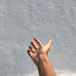 Cropped hand gesturing towards wall