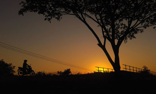 Silhouette trees on landscape against clear sky