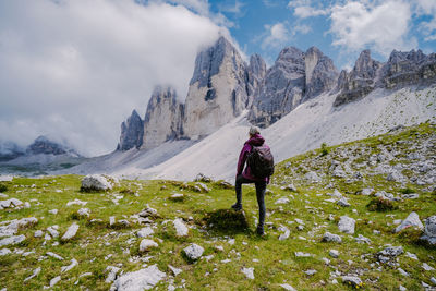 Rear view of man standing on mountain against sky