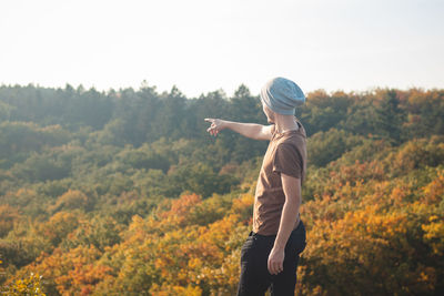 Attractive youthful man points to the leafy colourful trees . wild sarka, prague, czech republic