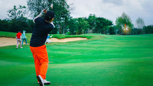 Man driving golf in a fairway, green and natural golf course in a daylight.