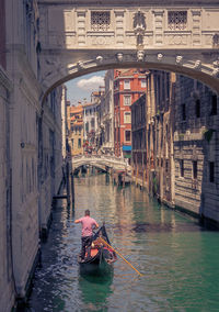 Boat in canal amidst buildings