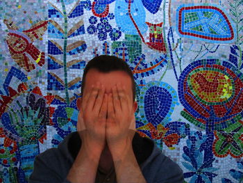Digital composite image of young man sitting against mosaic wall