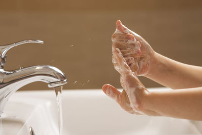 Midsection of woman with faucet in water