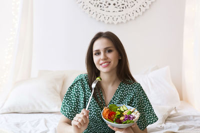 Portrait of a smiling young woman sitting on bed