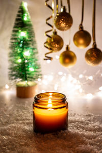 Warm night christmas decorations with candles, baubles and fir tree on magic bokeh background. 