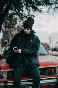 Portrait of man standing against car