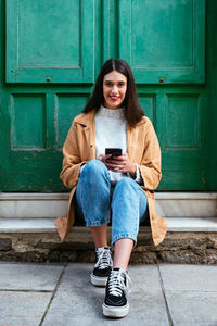 Portrait of teenage girl sitting on mobile phone