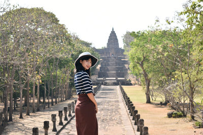 Young asian woman in white hat and striped shirt is exploring the ancient ruins