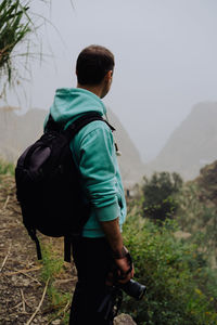 Side view of mid adult man standing on mountain during foggy weather