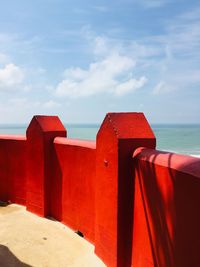 Red built structure on beach against sky