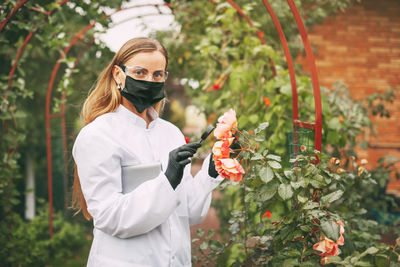 Woman holding umbrella while standing against plants