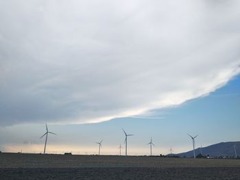 Wind turbines on field against sky