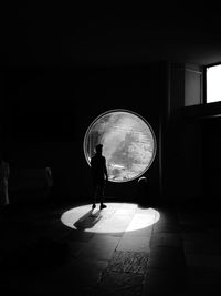 Silhouette of person standing by round window