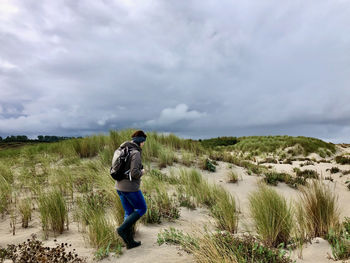 Rear view of man standing on land against sky