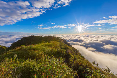 Scenic view of mountains against cloudy sky during sunny day