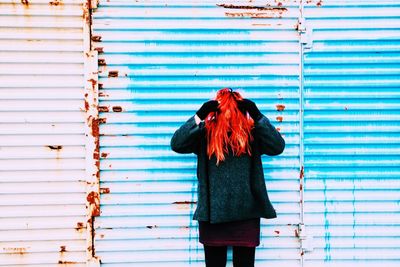Redhead woman standing against rusty corrugated iron door