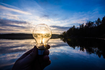 Light bulb held in front of the sun at sunset