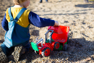 A toddler is playing with a truck and a digger. high quality photo