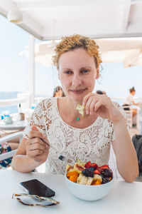 Portrait of young woman eating food at home