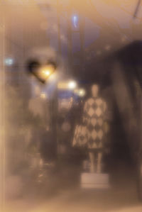 Defocused image of people seen through glass window at night