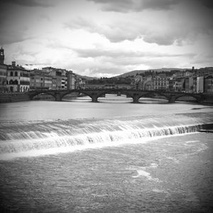 Bridge over river in city against sky