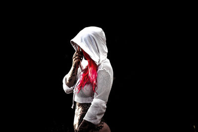 Side view of woman standing against black background