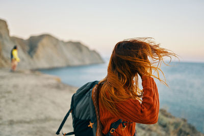 Rear view of woman at beach against sky