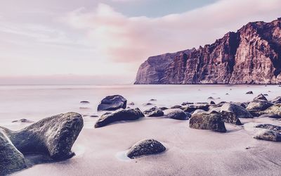 Scenic view of sea by cliff against sky