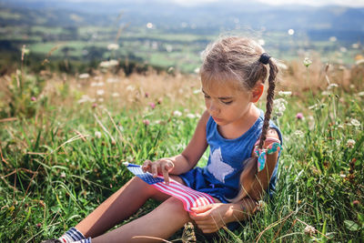 National flag day celebration. little patriot sitting on meadow and holding national flag of usa