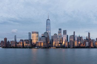 Illuminated buildings in city against cloudy sky