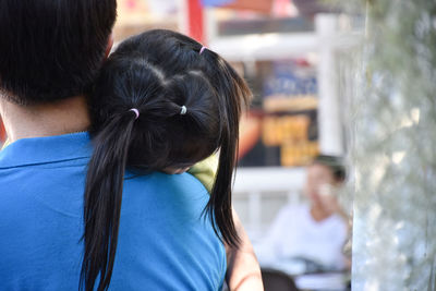 Rear view of father carrying daughter outdoors