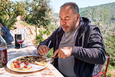 Man cutting pizza in the plate on tile table in the garden. homemade italian pizza. 