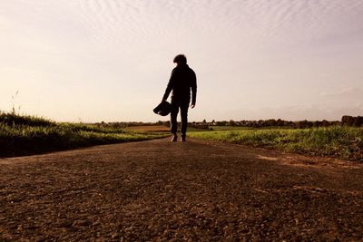 Full length of silhouette man walking on road against sky