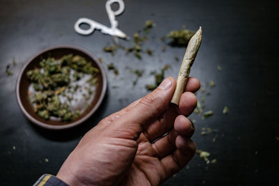 Cropped hands of man holding marijuana joint