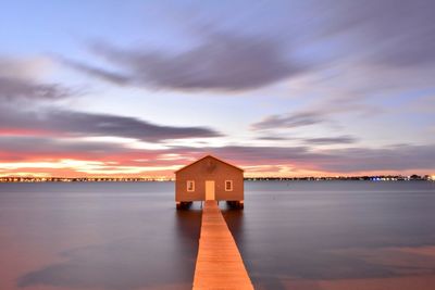 Narrow wooden jetty in calm sea at dusk