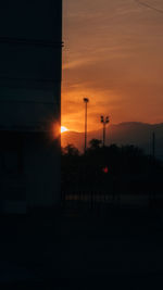 Silhouette street light against orange sky