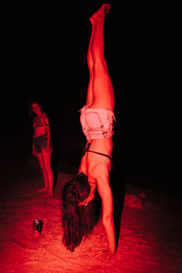 Midsection of woman dancing against black background