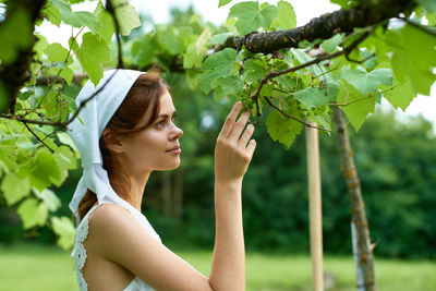 Portrait of young woman standing against trees