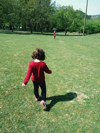 Rear view of girl walking on field in park