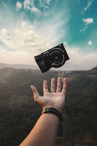 Midsection of person holding camera against sky