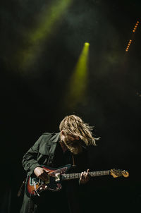 Low angle view of man playing guitar at night